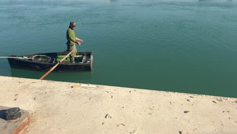 Crossing-the-waters-aboard-a-small-fishing-boat-with-a-lone-fisherman-aboard,-capturing-the-essence-of-a-small-coastal-fishing-community