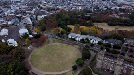 A-historic-building-amidst-autumn-colored-trees-in-a-city,-aerial-view