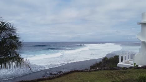 Ocean-waves-crashing-into-palm-tree-shore-drone-shot-pushing-in