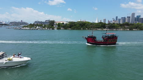 Touristic-Vintage-Pirate-Ship-in-Waterway-of-Miami-Bay,-Drone-Aerial-View-With-Downtown-in-Background,-Florida-USA