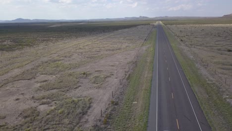 Drone-—-Highway-in-West-Texas-with-mountains-in-background-and-car-driving-through
