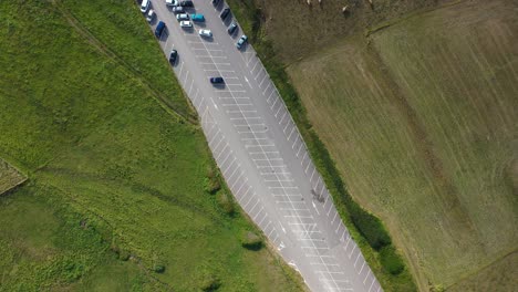 overhead-flight-with-meadows-in-one-there-are-cows-grazing-a-car-park-divides-them-and-we-arrive-at-a-beach-with-people-and-the-sea-with-waves-on-a-summer-afternoon-in-Cantabria-Spain