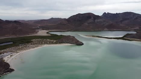 Playa-balandra-with-clear-turquoise-water-and-mountain-backdrop,-baja-california,-mexico,-during-the-day,-aerial-view