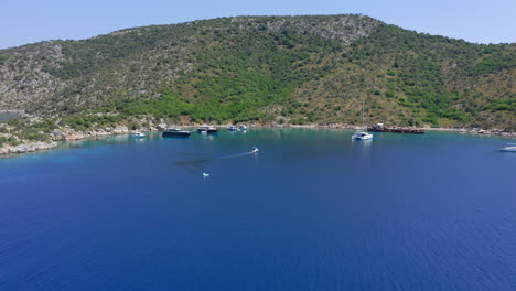 Aerial:-Small-boat-with-tourists-approaches-Peristera-island-shipwreck-beach-in-Sporades,-Greece