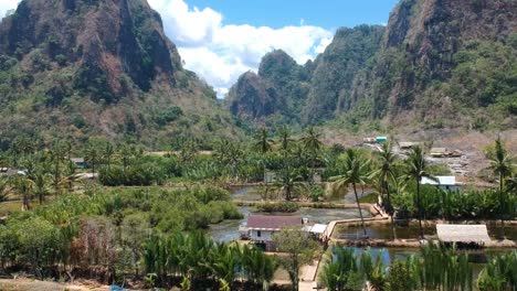 Aerial-of-beautiful-hidden-gem-Rammang-Rammang-Village-with-giant-limestone-cliffs,-traditional-houses-and-huge-karst-mountains-in-Sulawesi,-Indonesia