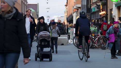 Couple-with-stroller,-bikes-and-scooters-on-shopping-street,-Sweden