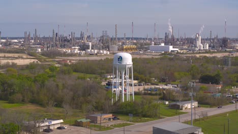 Drone-view-of-Baytown,-Texas-water-tower-and-refinery-in-the-background