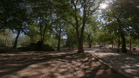 Eine-Drohne-Fliegt-Tief-über-Eine-Malerische-Brücke-Zwischen-Bäumen,-Neben-Einem-Historischen-Steingebäude-Im-Garten-Des-Marmolejo-Spa-Centers-In-Der-Provinz-Jaén,-Andalusien,-Südspanien