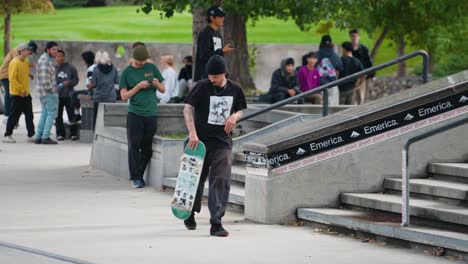 Ein-Junger-Mann-Vermeidet-Vor-Einer-Menge-Jugendlicher-Zuschauer-Unfälle,-Nachdem-Er-Mit-Seinem-Skateboard-Ein-Betongeländer-In-Einem-Skatepark-Hinuntergefahren-Ist