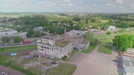 Orbit-View-over-Abandoned-Factory-next-to-Busy-Road-in-Cañuelas,-Argentina