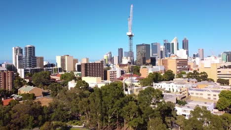 Dolly-right-aerial-view-of-East-Perth-construction-crane-with-tall-city-buildings-in-the-background