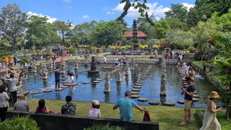 Palacio-De-Agua-Tirta-Gangga,-Isla-De-Bali,-Indonesia,-Gente-En-Escalones-En-Un-Estanque-Lleno-De-Carpas