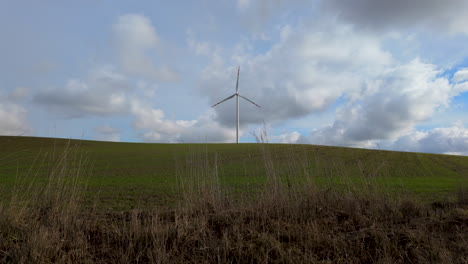 Turbina-Eólica-En-Una-Colina-Cubierta-De-Hierba-Con-Un-Fondo-De-Cielo-Nublado