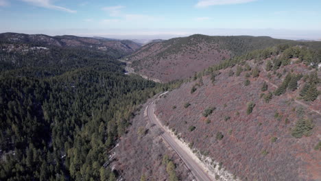 Ein-Auto-Fährt-Auf-Einer-Bergstraße-Mit-Wald-Darunter,-Drohnenluftaufnahme