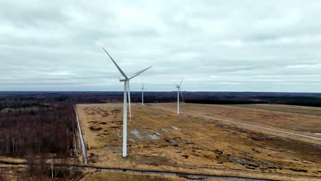 In-Der-Ferne-Sind-Drei-Windräder-Zu-Sehen,-Im-Hintergrund-Ein-Bewölkter-Himmel