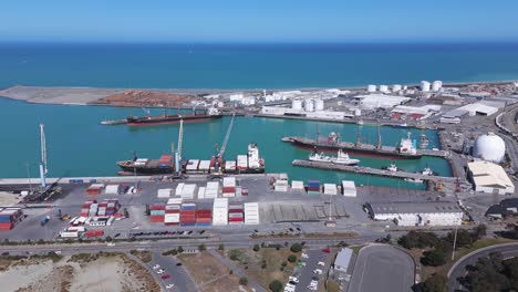 Puerto-De-Timaru-En-Nueva-Zelanda,-Contenedores-Y-Barcos-Atracados,-Océano-Azul,-Día-Soleado,-Industrial,-Vista-Aérea