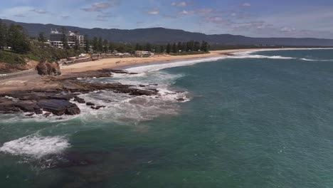 Luftaufnahme-Von-Menschen-Auf-Den-Felsen-Mit-Rettungsausrüstung-Fürs-Surfen-Im-Sand-Am-Strand-Von-North-Wollongong