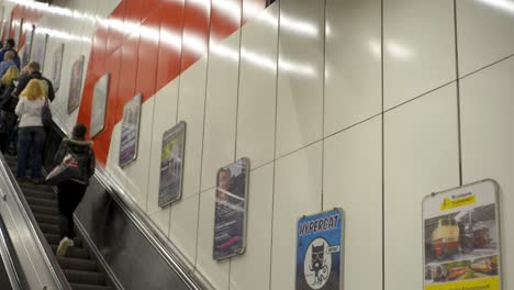 Pendler-Fahren-Eine-Rolltreppe-In-Einer-Stuttgarter-U-Bahnstation,-Plakate-An-Der-Wand,-Stadtverkehr-Szene