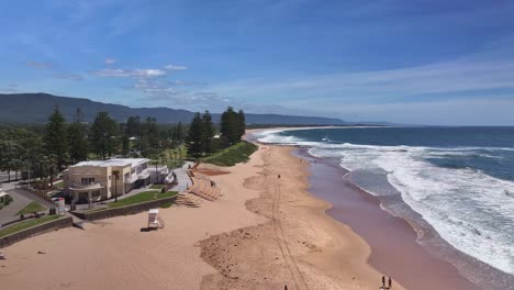 Sobre-Banderas-Que-Salvan-Vidas-Y-A-Través-De-La-Arena-Con-Bañistas-Disfrutando-De-Las-Condiciones-Soleadas-En-La-Playa-De-North-Wollongong.