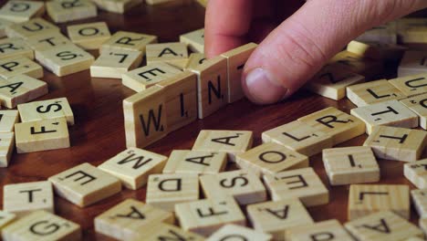 Right-hand-on-table-top-forms-word-WINTER-with-Scrabble-tile-letters