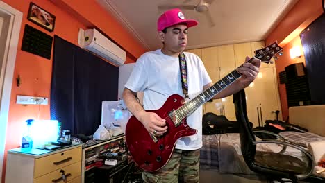 Indian-man-playing-electric-guitar-in-his-messy-bedroom-in-Gurgaon,-India