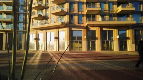 People-walking-by-as-silhouette-in-sunlight-backlight-reflection-in-modern-apartment-building