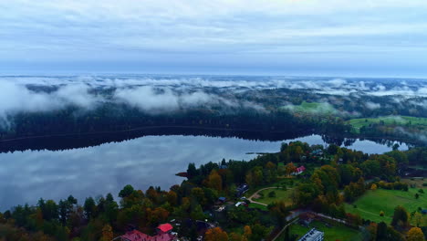 Paso-Aéreo-Lento-Del-Lago-Raiskuma,-Casas-De-Vacaciones-Junto-Al-Lago,-Cubierta-De-Nubes-Colgando-Sobre-Un-Lago-Cristalino