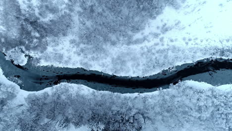 Frozen-scenery-from-atop,-aerial-view-of-icy-midwinter-landscape,-river-break-through