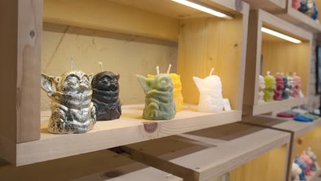 Velas-De-Personajes-Yoda-Inspiradas-En-La-Fantasía-En-Un-Estante-De-Madera,-Tienda-La-Candela-De-Venecia