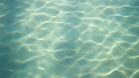 Reflexionen-Und-Bewegungen-Von-Der-Wasseroberfläche-Im-Wasserbecken,-Sichtbar-Am-Boden-Durch-Sonnenlicht