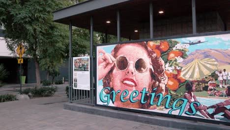 Greeting-mural-in-Palm-Springs,-California-with-cars-driving-by-and-stable-video