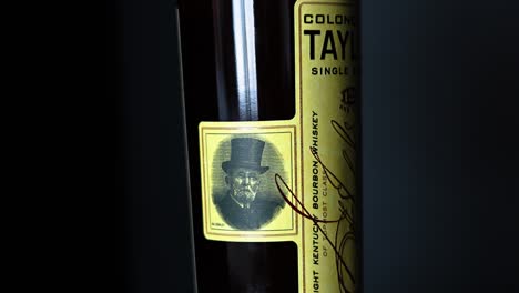 Botella-De-Whisky-Bourbon-Puro-Eh-Taylor-Kentucky-Cerca-Del-Retrato-Del-Coronel-Edmund-Haynes-Taylor-En-El-Costado-De-La-Botella-Con-Un-Fondo-Negro