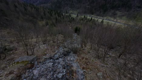 FPV-drone-view-descending-over-rocky-surface-of-water-stream-in-Val-di-Mello-in-Northern-Italy
