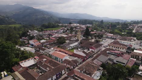 Toma-Aérea-En-órbita-De-La-Iglesia-De-Nuestra-Señora-Del-Carmen-En-La-Ciudad-De-Salento-Con-Montañas-Al-Fondo,-Colombia