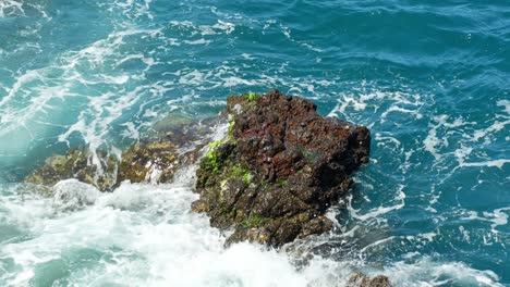 Waves-of-Dark-Blue-Sea-Water-Crashing-Against-Rocks-in-a-Sunny-Resort