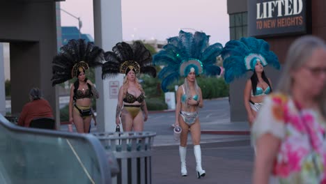 Un-Grupo-De-Mujeres-Caminando-Por-La-Calle-Vistiendo-Trajes-Con-Tocado-De-Plumas-En-Las-Vegas,-EE.UU.