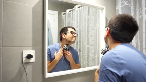 Man-connecting-the-charger-of-the-shaver-to-continue-shaving-his-beard