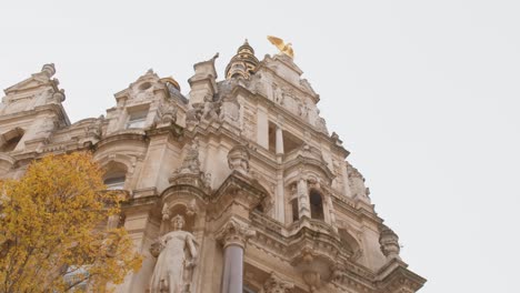 Medieval-facade-building-with-statues-and-golden-bird-looking-up-with-a-slight-tilt-upwards-in-Antwerp