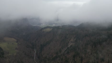 Fly-through-misty-low-clouds-in-scenic-European-mountains-above-leafless-forest-canopy-in-valley