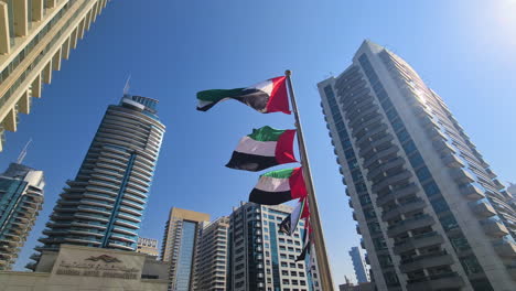 Nationalflaggen-Der-Vereinigten-Arabischen-Emirate-Wehen-Auf-Einem-Mast-In-Einem-Luxuriösen-Wohnviertel-In-Dubai,-Niedriger-Winkel