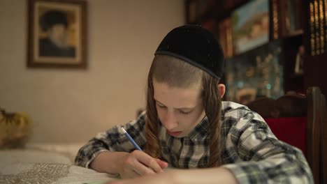 A-jewish-12-year-old-boy-is-sitting-by-a-table-and-writing