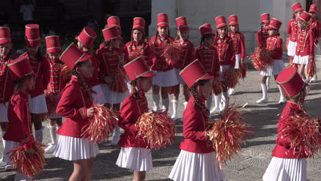 Chicas-Majorettes-Con-Uniformes-Rojos-Marchando-Con-Pompones.