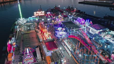 Genova-Winter-Park-with-illuminated-rides-on-Ponte-Parodi,-aerial-tilt-up