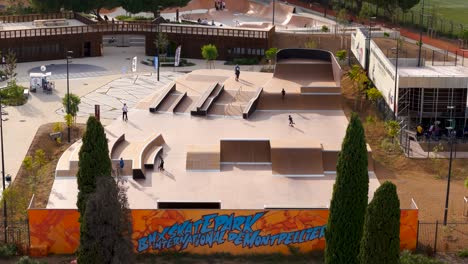 Aerial-view-above-the-outdoor-skatepark-of-Montpellier,-people-skating,-stepping-and-biking