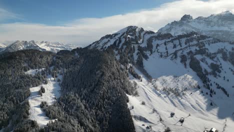 Luftaufnahme-über-Schneebedeckten-Bergen-Und-Kiefernwäldern,-Lange-Schatten,-Die-An-Einem-Tag-Mit-Blauem-Himmel-Vom-Bergrücken-Geworfen-Werden