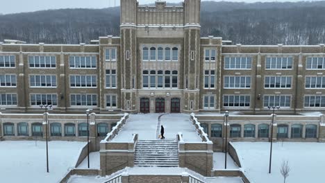 Person-shoveling-entrance-to-large-American-high-school-during-snow-day