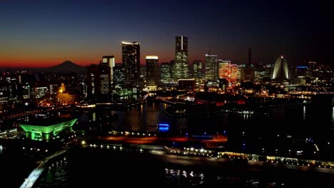 Sunset-skyline-of-a-bustling-city-with-lights-reflecting-on-water,-Mt