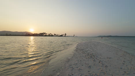 Sonnenuntergang-über-Dem-Strand-Mit-Sanften-Wellen-Und-Einer-Tropischen-Insel-In-Der-Ferne