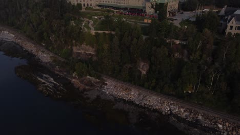 drone-reveals-Fairmont-Le-Manoir-Richelieu,-Charlevoix,-Quebec-Canada-famous-luxury-hotel-resort-attraction-aerial-footage-at-sunset-illuminated-at-night