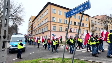 Angry-Farmers-Protest,-Crowd-Of-People-Walks-Through-The-City-Center,-Police-Escort